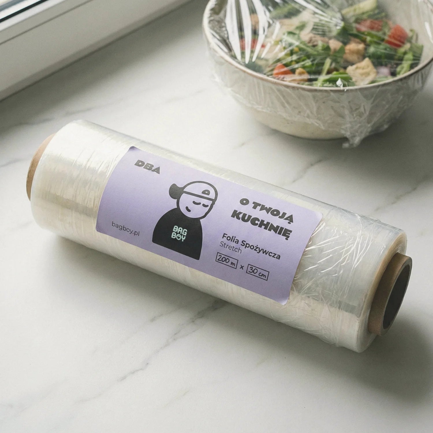 Folia spożywcza stretch BagBoy 200m × 30cm – rolka z etykietą na marmurowym blacie.